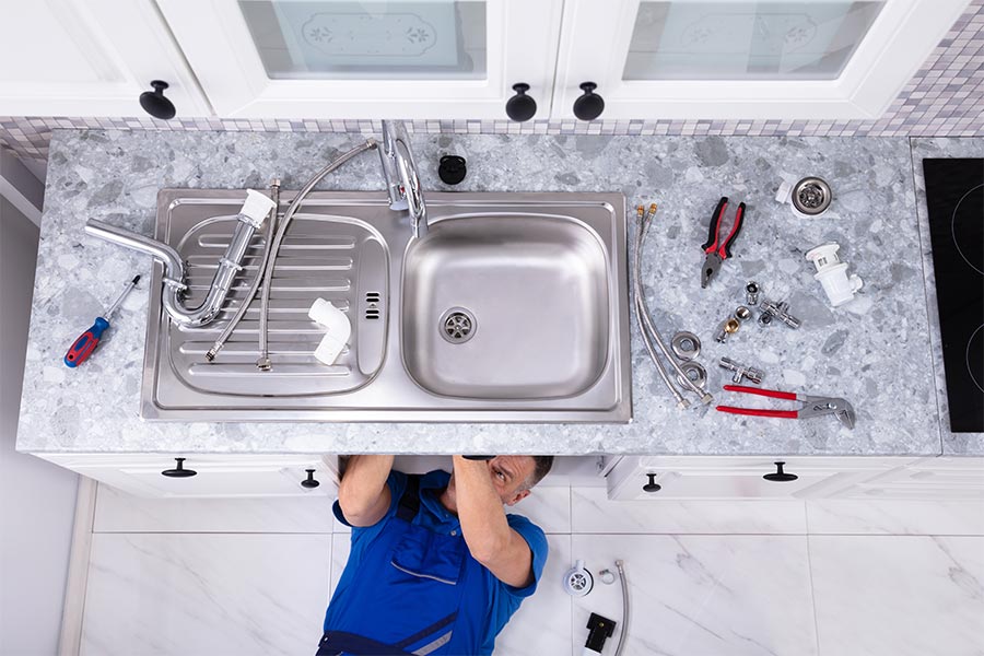 Tech under sink fixing plumbing